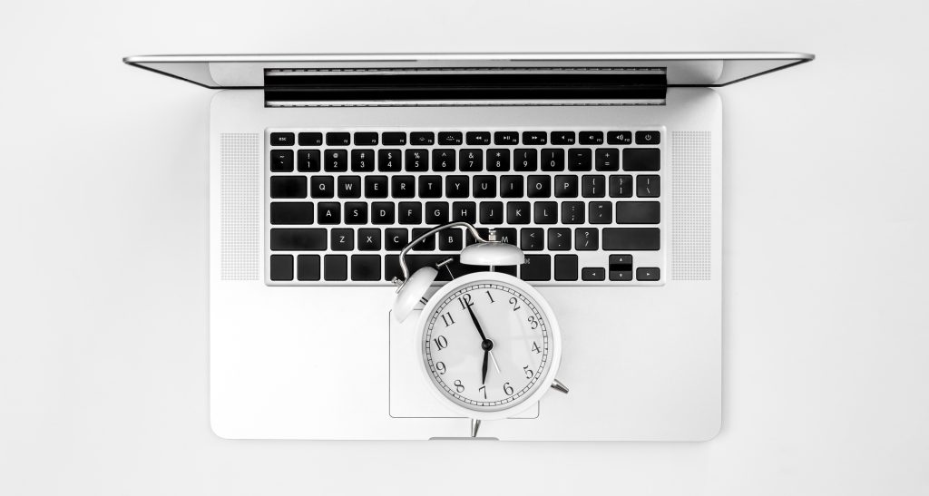 sveglia e un computer portatile su una vista superiore del fondo bianco